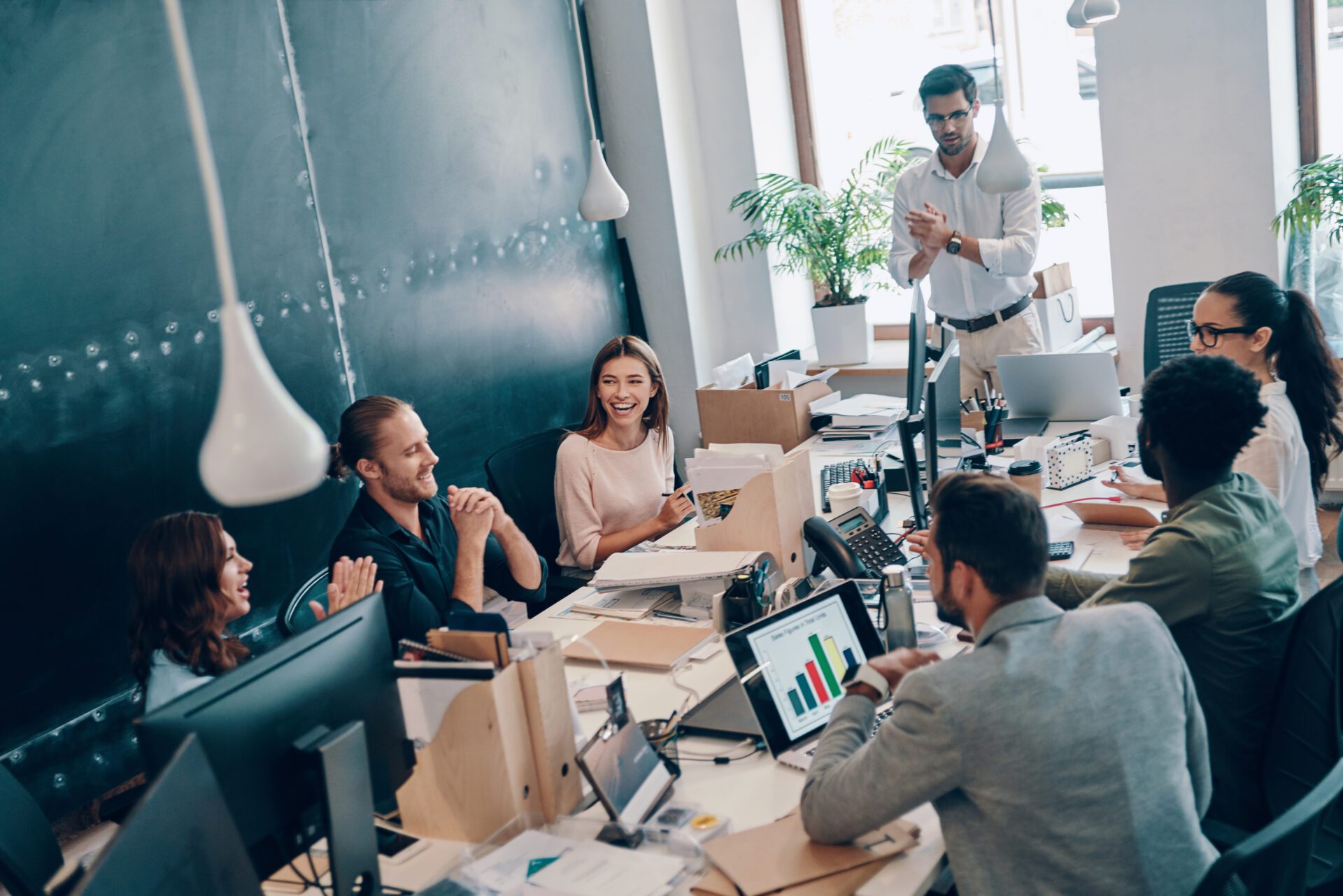 Group of young modern people in smart casual wear communicating and using modern technologies while working in the office